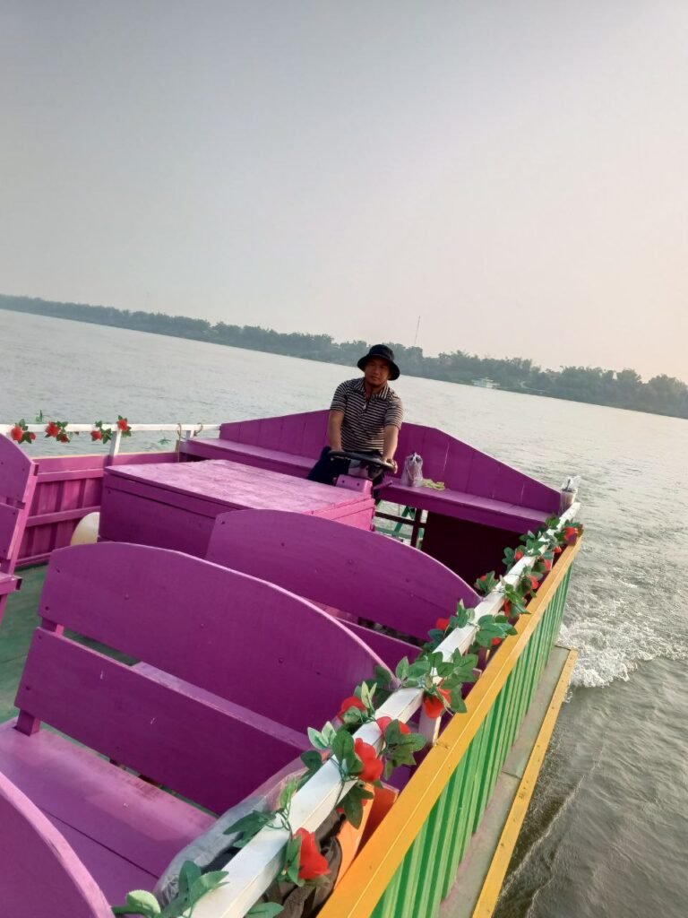 A wooden river boat painted bright purple and pink on the Mekong River.