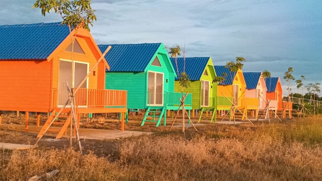 Row of colorful A-frame tiny homes painted orange, green, and blue.