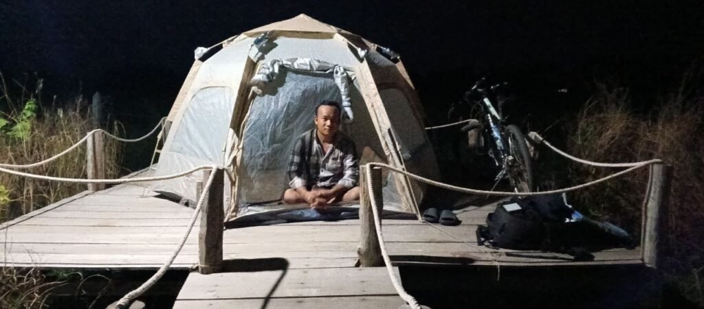 Sleeping in a beige camping tent on a wooden deck with a bicycle during early business startup phase.