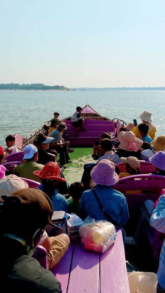 ourists riding a bright pink boat on the Mekong River during a sunny day.