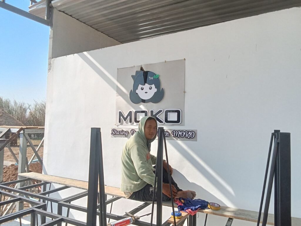 Phonh sitting next to the MOKO logo sign during construction, demonstrating simple and memorable branding.