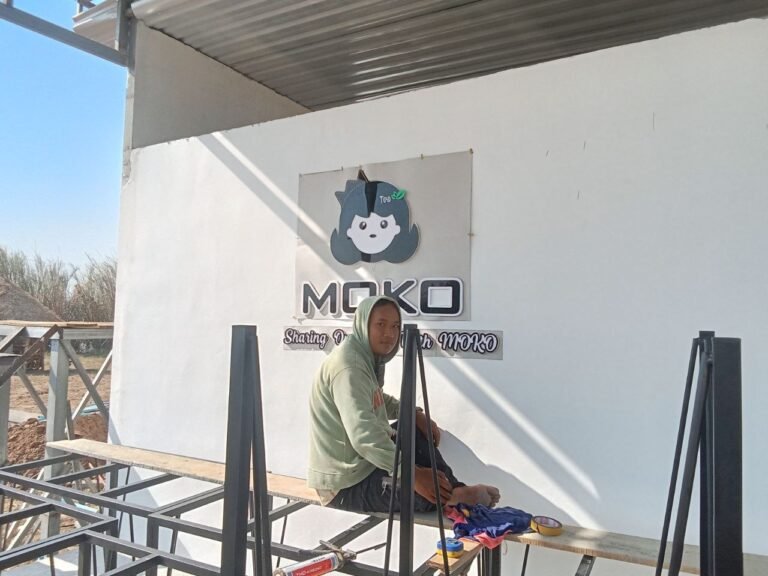 Phonh sitting next to the MOKO logo sign during construction, demonstrating simple and memorable branding.