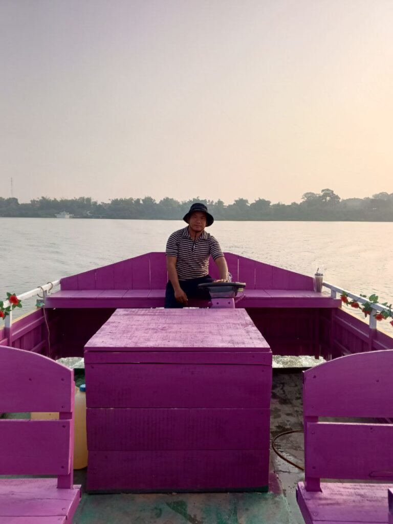Business owner Phonh driving his bright pink boat on the Mekong River, demonstrating unique small business branding.