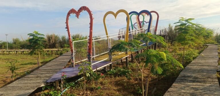 How to Build a Photo Spot for a Resort: Our Rainbow Heart Gate Story Entrance to the rainbow heart gate showing a red metal heart decorated with flowers and a wooden walkway painted purple and yellow.