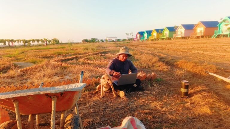 Me working on my laptop in the dirt with my dog Dudo sitting beside me.
