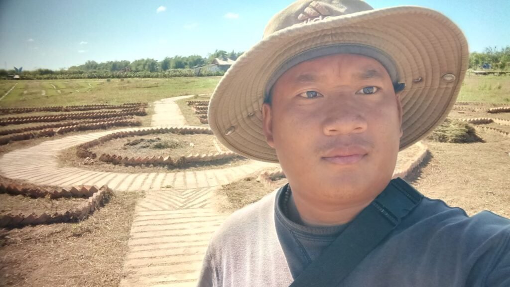 Garden owner wearing a sun hat standing in a dry, empty field during early construction stages.